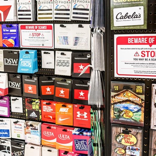 A gift card stand displays scam warning.