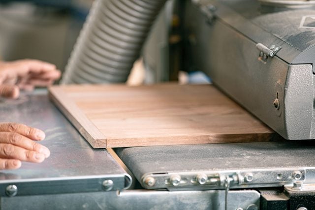 wooden panel being ran through sander